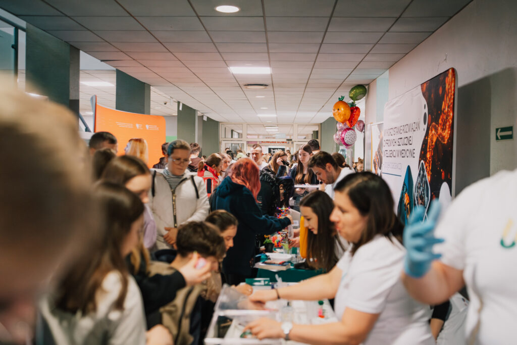 hol wypełniony uczesntnikami dnia otwartego; po jednej stronie ustawione są stoiska wystawiennicze; po bokach widać ścianki promocyjne Lubelskiej Unii Cyfrowej